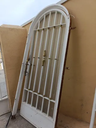 Puerta de entrada con reja y cristal. Con marco.