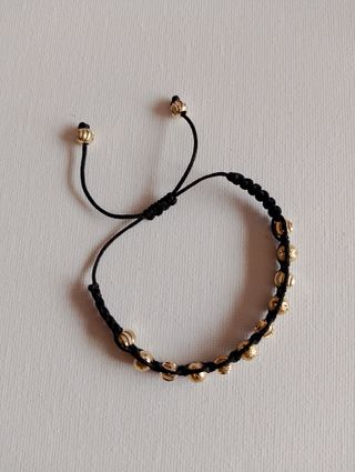Pulsera negra con cuentas doradas