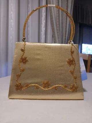 Elegante bolso de mano y de hombro dorado con abal