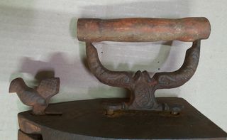 Plancha antigua de hierro con adorno de pájaro