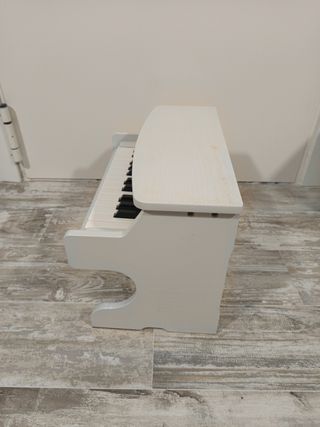 Piano infantil de madera blanco.