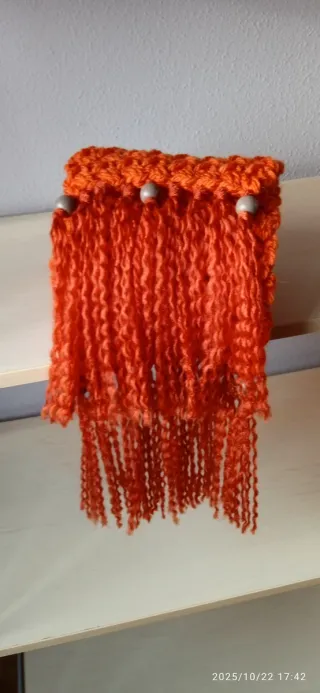 Bufanda tejida naranja con flecos.