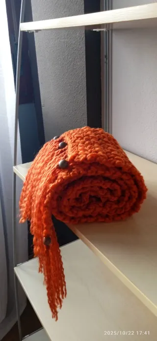 Bufanda tejida naranja con flecos.