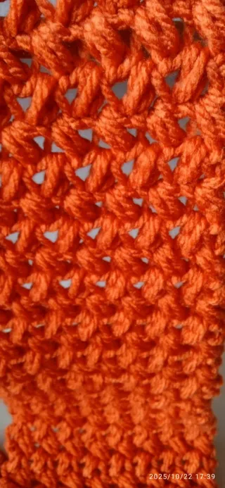 Bufanda tejida naranja con flecos.