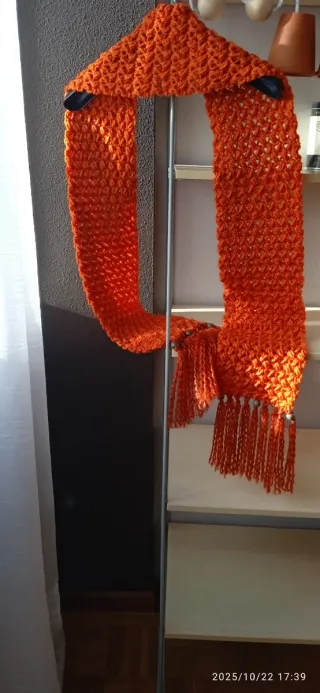 Bufanda tejida naranja con flecos.