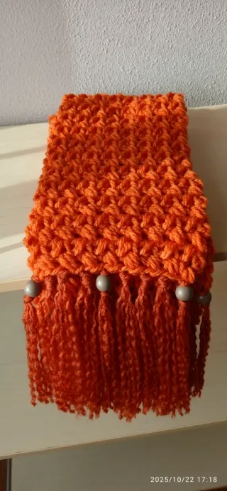 Bufanda tejida naranja con flecos.