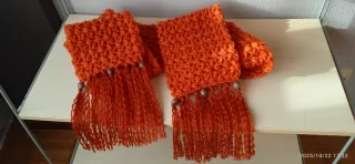 Bufanda tejida naranja con flecos.