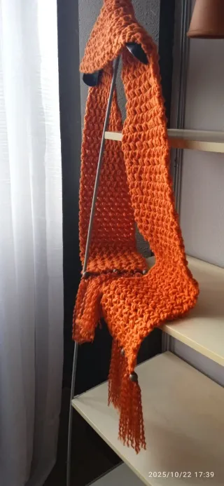 Bufanda tejida naranja con flecos.