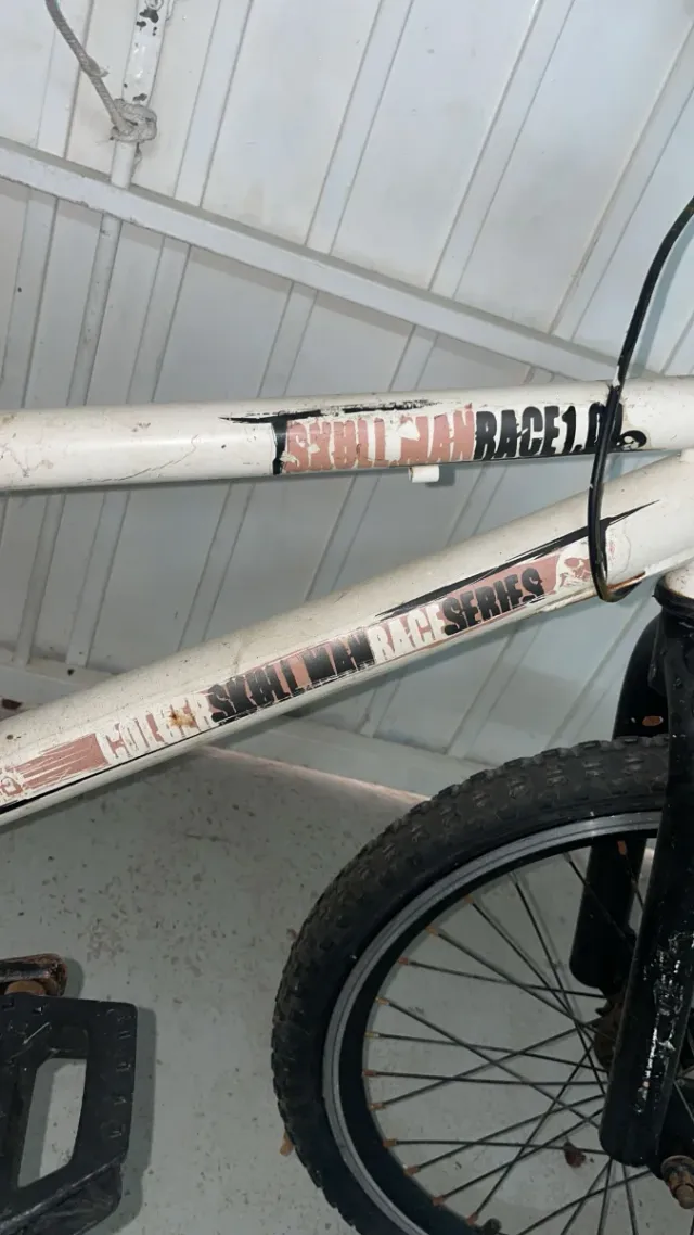 Bicicleta BMX branca. Tem pneus furados