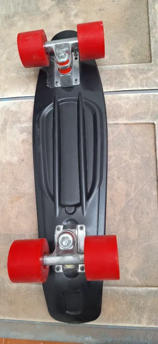 Monopatín negro con ruedas rojas