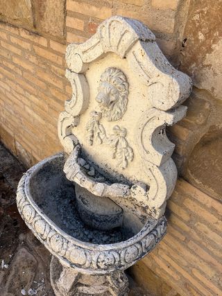 Fuente de pared de piedra con león