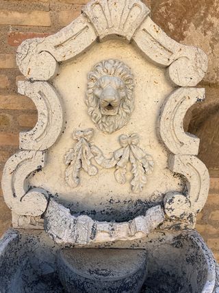 Fuente de pared de piedra con león