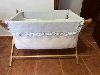 Minicuna con fundas celestes y blancas.