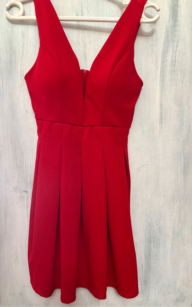 Vestido rojo escotado con falda plisada.