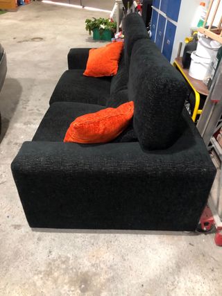 Sofá negro de tres plazas con cojines naranjas