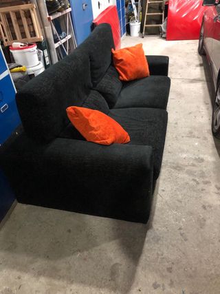 Sofá negro de tres plazas con cojines naranjas