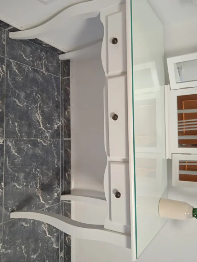 Elegante tocador con superficie de cristal.