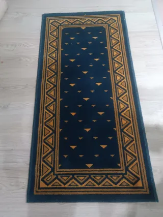 Alfombra azul y dorada con diseño geométrico.