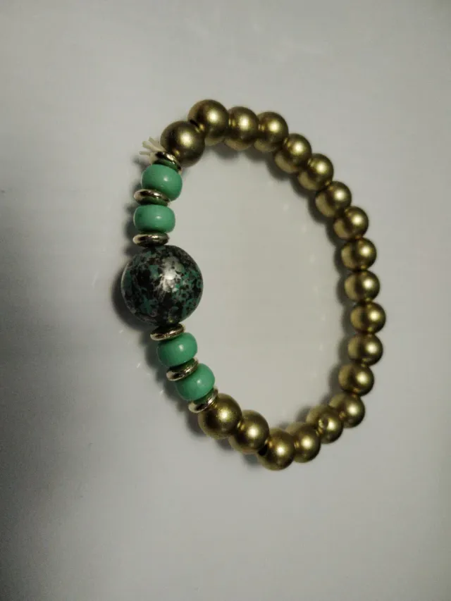Pulsera dorada con detalle turquesa