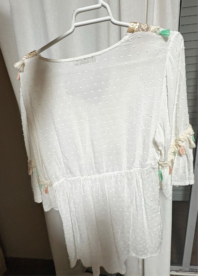 Blusa blanca con detalles dorados y flecos