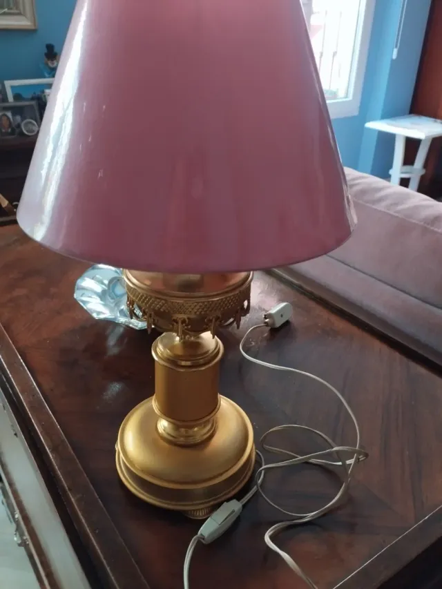 Lámpara dorada con pantalla rosa.