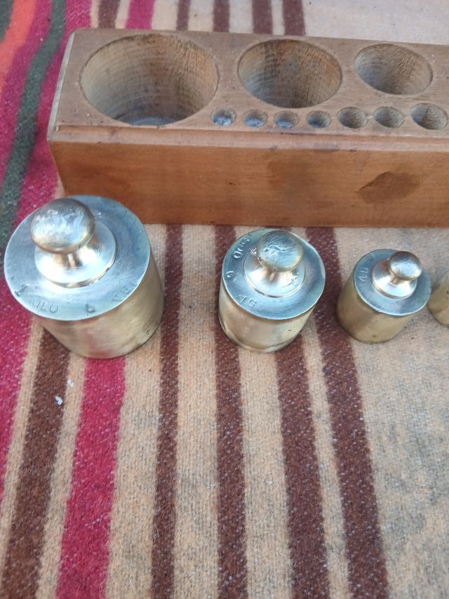 Caja con 9 pesas de balanza de bronce
