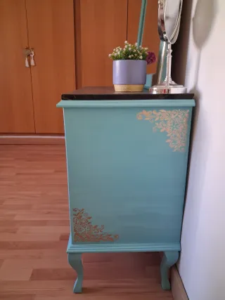 Tocador azul con espejo y detalles dorados.