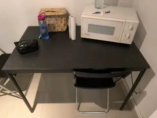 Mesa negra con microondas blanco