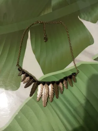 Gargantilla dorada con plumas y detalles negros
