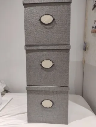 Caja de almacenaje gris con tapa y etiqueta.