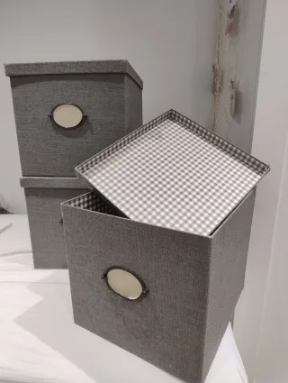 Caja de almacenaje gris con tapa y etiqueta.