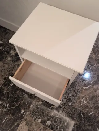 Mesita de noche blanca de madera con un cajón.