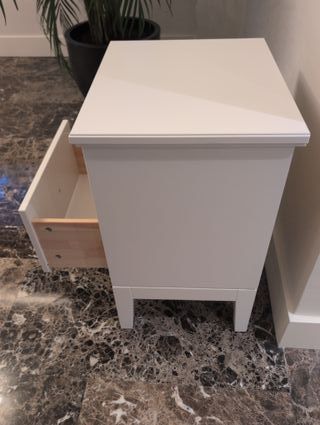 Mesita de noche blanca de madera con un cajón.