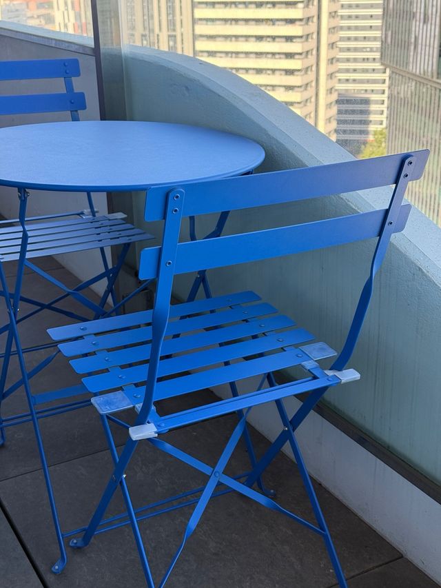 Mesa redonda (60cm) y sillas plegables azules.