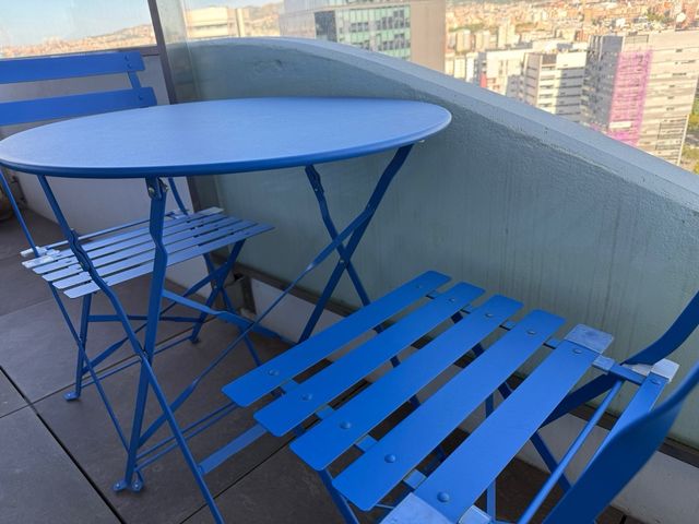 Mesa redonda (60cm) y sillas plegables azules.