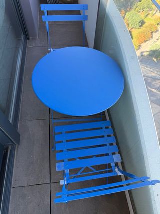 Mesa redonda (60cm) y sillas plegables azules.