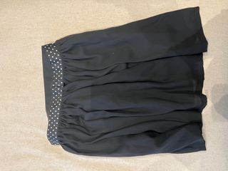 Falda negra suelta por encima de la rodilla