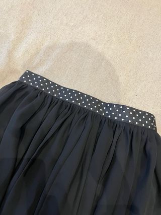 Falda negra suelta por encima de la rodilla