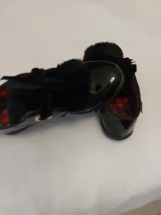 Zapatos negros de charol con flecos y lazo