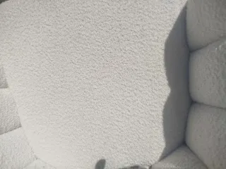 Sillón blanco estilo concha con patas doradas.