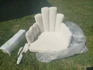 Sillón blanco estilo concha con patas doradas.