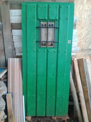 Puerta rústica verde con reja