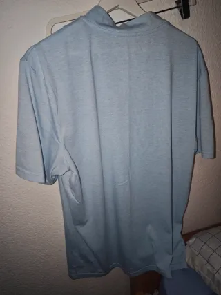 Camiseta azul con águila y texto.