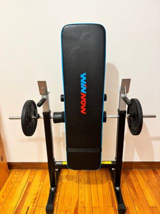 Banco de gimnasio con barra y discos