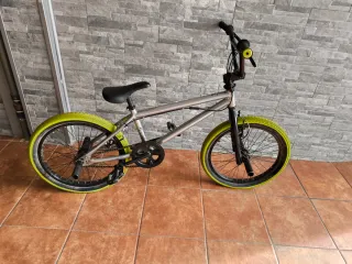 Bicicleta BMX plateada con ruedas verdes
