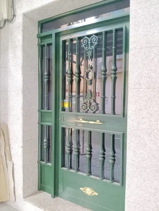 Puerta de casa verde con rejas