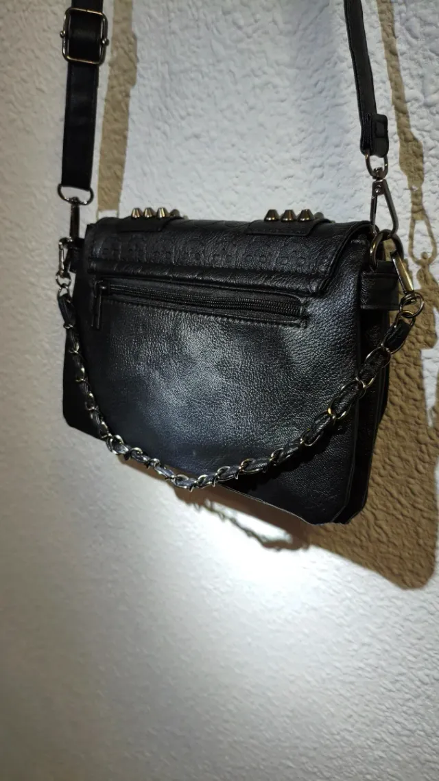 Bolso negro con tachuelas y calaveras.