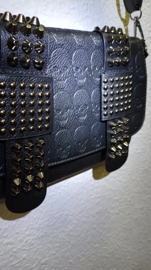 Bolso negro con tachuelas y calaveras.