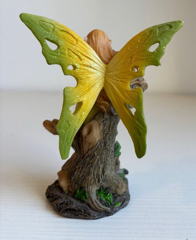 Fatina verde seduta su tronco con fiori