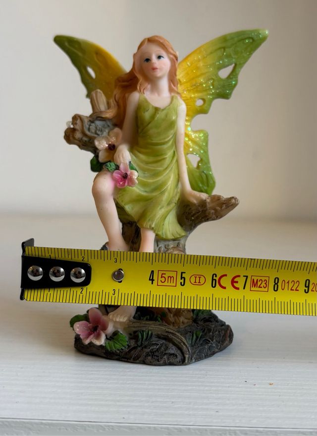 Fatina verde seduta su tronco con fiori